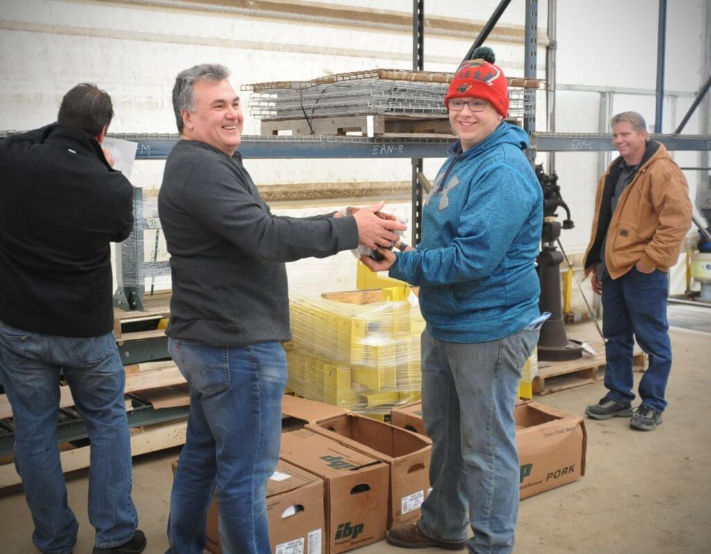 Frank Sterner, second from the left, hands a ham to Ethan Heimkes, second from the right, for his holiday bonus. Also pictured are Ed Salonek, left, and Brian Springer, right.